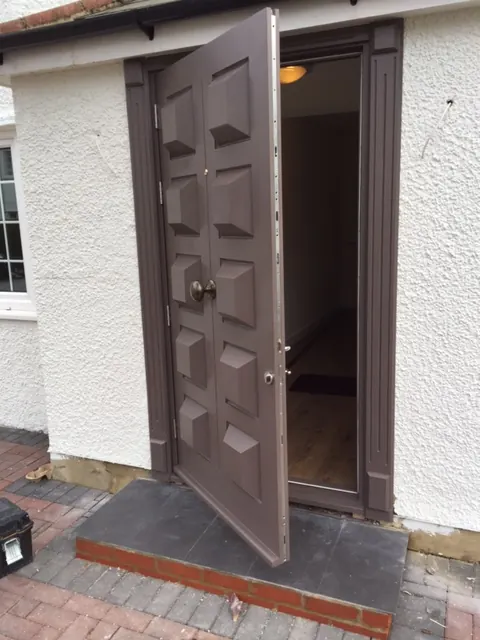 Bespoke mocha-brown panelled timber front door, open, with brass door furniture